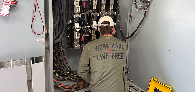 Technician performing preventative maintenance inside a control panel